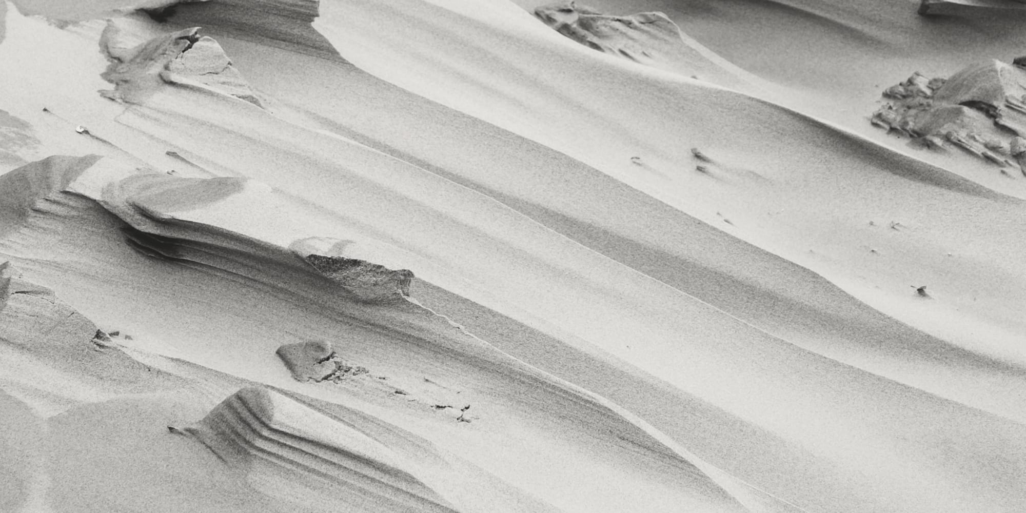 Black and white image of sand dunes with smooth curves and textures